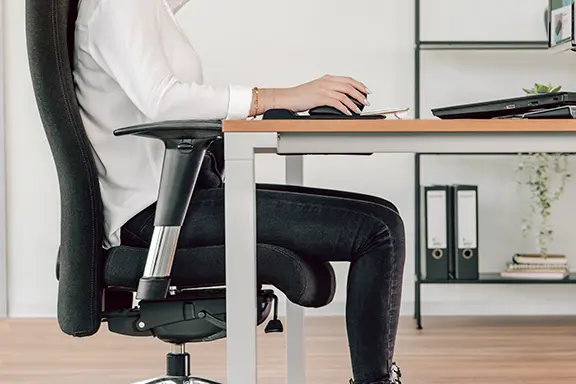 Person sits upright at the desk.