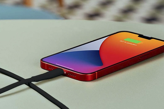 Apple smartphone lies on a table and is charged via the Hama "Fabric" charging cable
